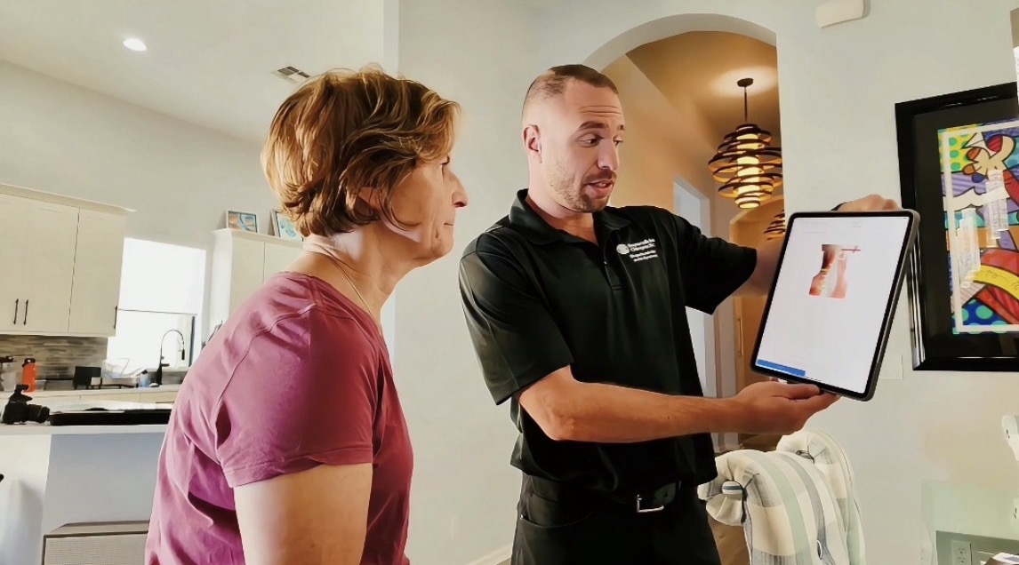 Dr. Gordon reviewing exam findings with a patient on a tablet inside her home